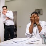 man in white dress shirt covering his face